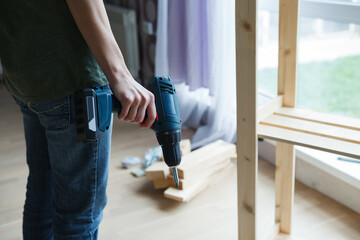 Young woman hand holding electric drill ready to make wooden furniture