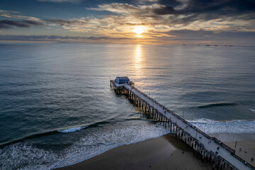 Poster - Picturesque view of a sandy beach with a wooden pier stretching out into the bright blue ocean