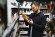Young man looking at bottle of wine in supermarket