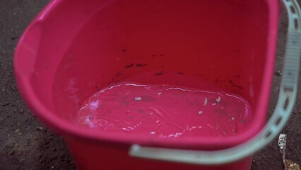 Canvas Print - Close-up of water droplets dripping into a red bucket