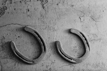 Canvas Print - Old vintage used horseshoes for western industry background with copy space on texture in black and white.