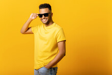 Overjoyed Indian Man Wearing Sunglasses Looking At The Camera, Smiling Positively, Being In High Spirit. Carefree Hispanic Guy In Yellow T-shirt Isolated, Having Summer Mood