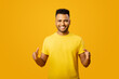 © Vadim Pastuh - Young handsome Arab man measuring empty space, showing size standing isolated on yellow, cheerful indian man holding hands in front of him, sizing wide