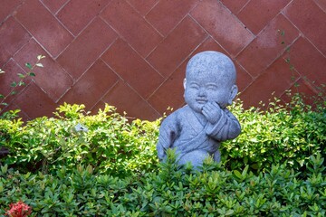 Sticker - Baby Buddha statue in the garden surrounded by plants