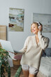 © LIGHTFIELD STUDIOS - happy young woman in wireless headphones listening music and holding laptop in modern bedroom.