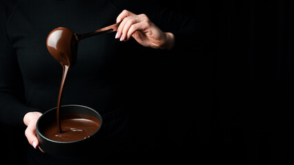 the chef scoops hot chocolate into a bowl. on a black background. preparation of chocolate.