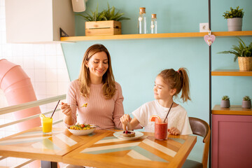 Mother and daughter having a breakfast with fresh squeezed juices in the cafe