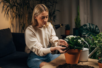 Wall Mural - A blonde woman fills up the flowerpot with dirt