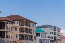 Villas And Beach Houses In A Row In Destin, Florida. Row Of Beach House And Resort Buildings With Balconies Against The Clear Blue Sky Background.
