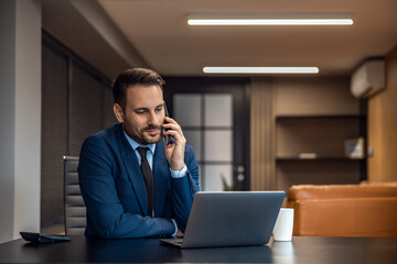 Young ceo using smartphone and laptop his office