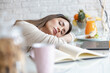 © ivanko80 - Tired young woman with book sleeping on desk at home