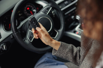 Close up of woman holding keys to rental car before trip and smiling at camera