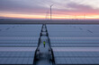 © Jordi Huisman - A construction working walks through a solar field with the solar panels covered in snow. They don’t produce any power like this. Wind turbines for power production are seen at the horizon.
