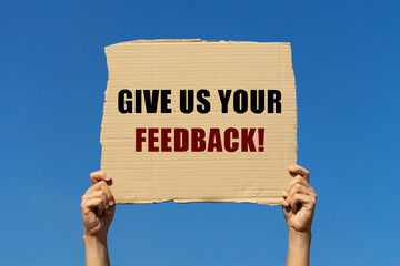 Give us your feedback text on box paper held by 2 hands with isolated blue sky background. This message board can be used as business concept to inform audience to provide feedback.