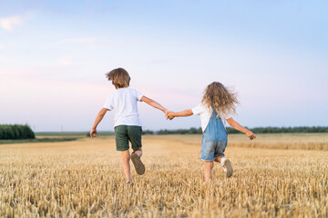 Happy and free people, children run through the beveled field of wheat, people from behind