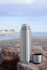 Sticker - Metallic thermos and cap on stone near sea