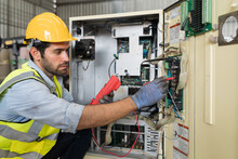 Male Electrician Worker Checking, Repair, Maintenance Operation Electric System In Factory. Male Electrician Using Electrical Meters Working With Operation Electric System In Workshop