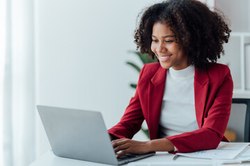 happy young businesswoman African American siting on the chiar cheerful demeanor raise holding coffee cup smiling looking laptop screen.Making opportunities female working successful in the office.
