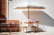 Chair and table with umbrella in front of white wall. Summer place for cafe hopping or restaurant. Generative AI.