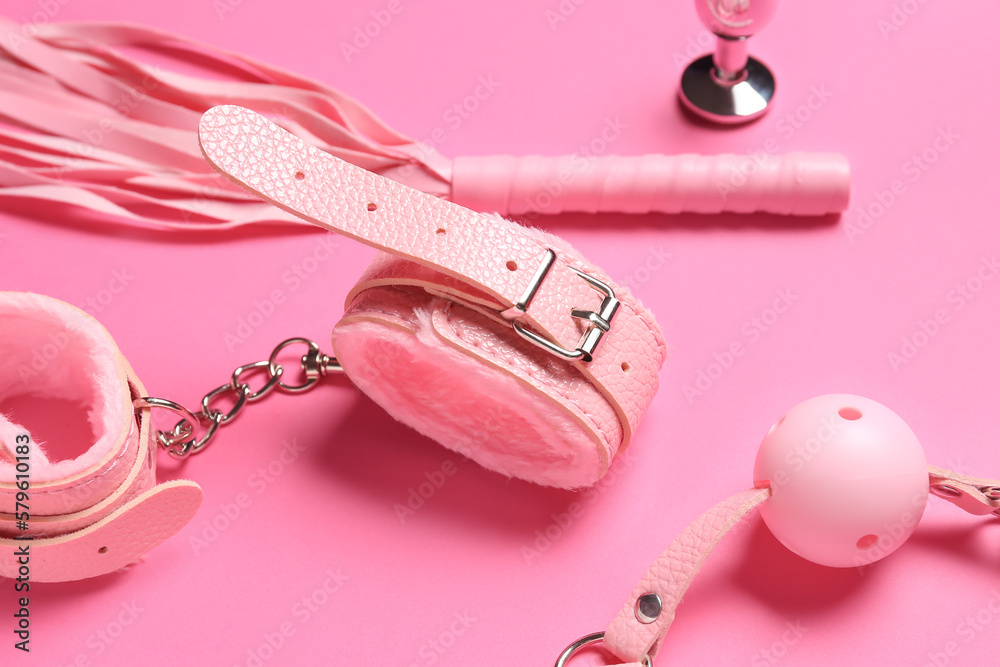 Different sex toys on pink background, closeup