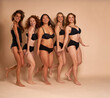 © gpointstudio - Group of cheerful women in black underwear standing and smiling towards the camera