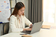 © Prathankarnpap - Focused female employee checking financial documents, working with laptop computer at her office desk