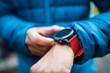 © Cavan Images - Midsection of man wearing warm clothing wearing smart watch while standing outdoors