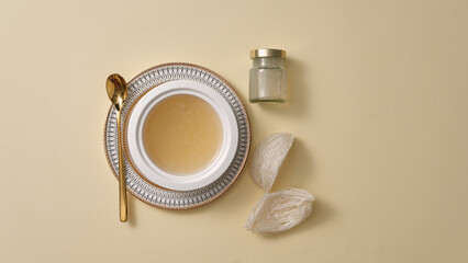 Wall Mural - Top view of raw bird’s nest , bowl soup, and glass bottle without label on beige background. Mockup for products derived from natural bird's nest