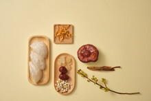Bird's Nest Placed On A Wooden Plate And Next To It Is Cordyceps, Lingzhi Mushroom, Ginseng And A Dish Of Herbs, Decorated With Flower Branch. A Luxury Combination For Health, Body And Skin