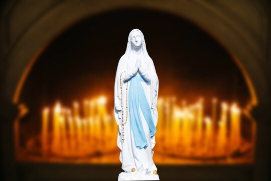 Mother Mary pray. Blessed virgin statue. Praying Virgin Mary statue. Religious background. Empty copy space faith background. Saint sculpture isolated on candles background.