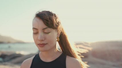 Poster - Meditation, yoga and fitness with woman at beach for spiritual, mindfulness and peace. Wellness, freedom and windy with girl breathing on rocks in nature for faith, summer break and calm mindset