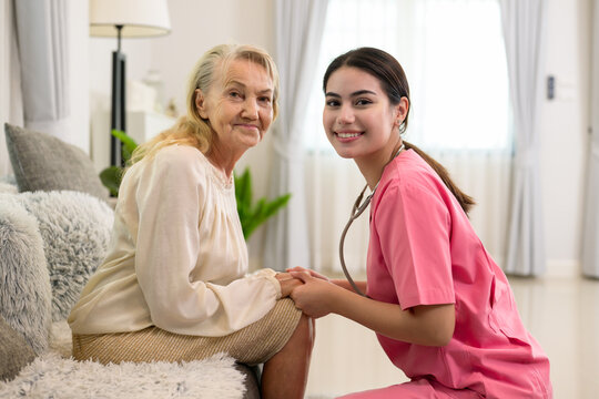 happy senior woman talking with female caregiver in living room