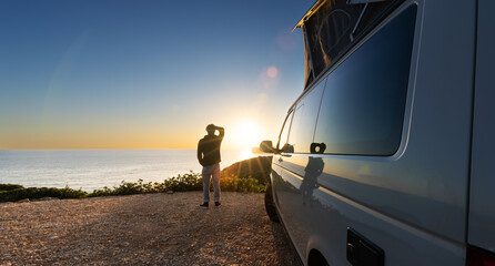 man standing with digital device at his Transporter Camping Van bus at the California Ocean in the coastal Nature - digital nomad concept