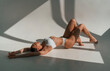 Peaceful mood. Lying down on the floor. Young caucasian woman with slim body shape is indoors in the studio