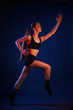 © standret - Running, conception of sports. Beautiful muscular woman is indoors in the studio with neon lighting