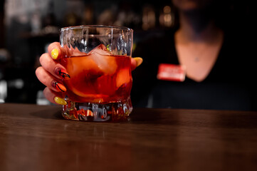 Wall Mural - woman hand bartender holding glass negroni cocktail