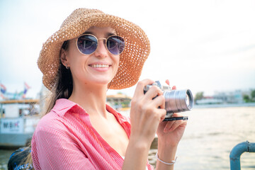 Fototapete - Beautiful woman take photo with camera travel in city river side