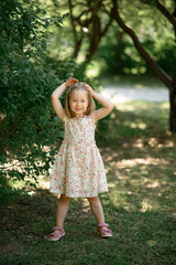 Little girl 3 years old in a summer sundress in the park. Summer time.