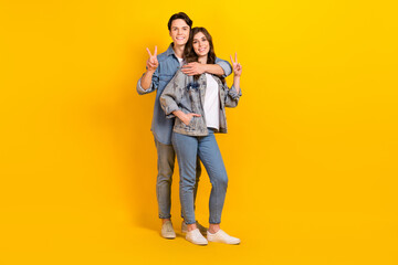 Poster - Full length photo of sweet pretty couple wear jeans showing v-signs cuddling isolated yellow color background