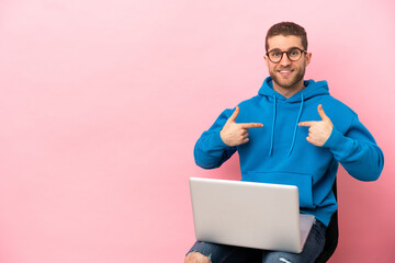 Poster - Young man sitting on a chair with laptop with surprise facial expression