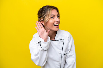 Sticker - Uruguayan chef woman isolated on yellow background listening to something by putting hand on the ear