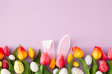 Wall Mural - Easter concept. Top view photo of rabbit bunny ears colorful easter eggs and tulips flowers on isolated lilac background with empty space