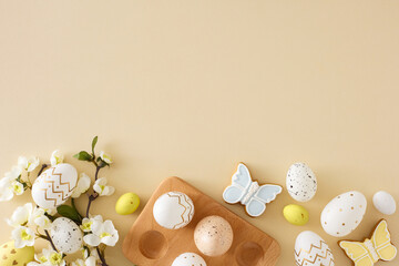 Wall Mural - Easter decor concept. Flat lay photo of colorful easter eggs in wooden holder butterfly shaped cookies and spring blossom branch on isolated beige background with copyspace