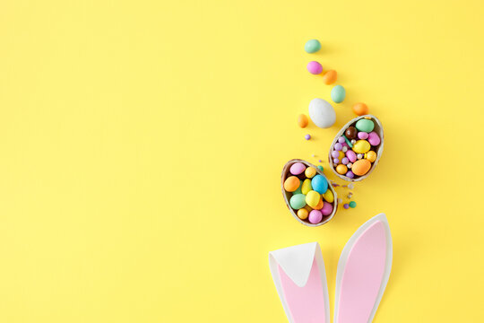 easter celebration idea. top view photo of easter bunny ears chocolate eggs with сolorful dragees an