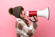 Little Caucasian Girl With Winter Jacket Isolated On Pink Background Shouting Through A Megaphone