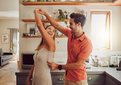 joyful, dancing and loving couple bonding and having fun in the kitchen together at home. energetic,