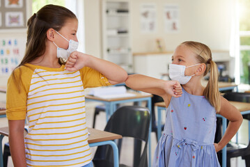 Poster - Covid greeting, elbow bump and mask wearing with little girl students standing in class at school. Study, education and safety in a classroom with a female child and her friend bumping elbows