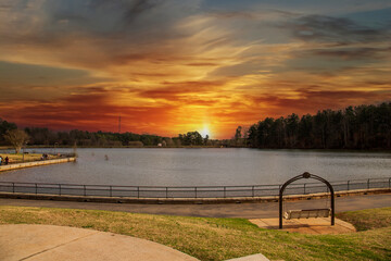 Wall Mural - a gorgeous winter landscape at Rhodes Jordan park with a blue lake, yellow winter grass lush green trees, people walking and blue sky with powerful clouds at sunset in Lawrenceville Georgia USA