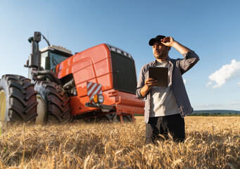 Sticker - Farmer with a digital tablet on the background of an agricultural tractor