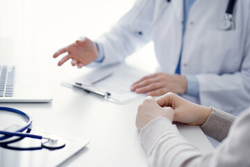 Doctor and patient discussing current health questions while sitting at the table in clinic office, only hands closeup. Medicine concept.